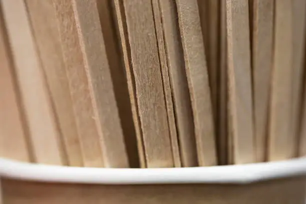 Wooden stir sticks in paper glass. Sticks for coffee