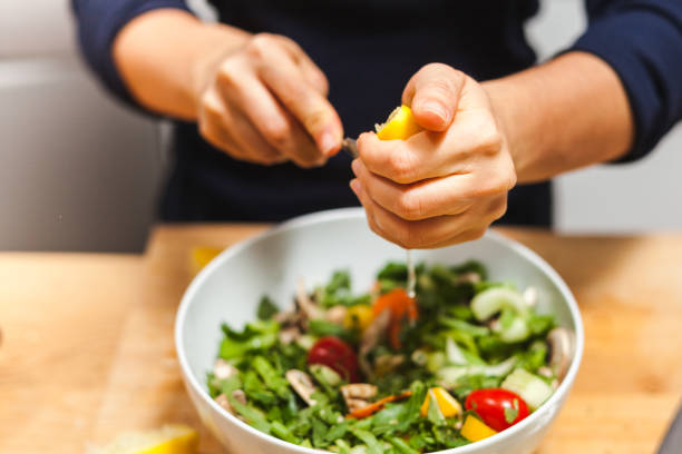 istock Woman hands squeezing fresh lemon juice into salad bowl 1224154644