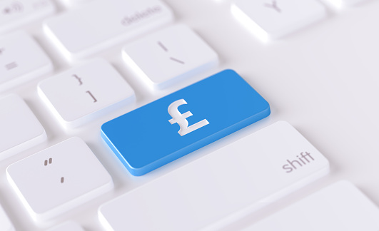 British pound icon written on a blue button of a computer keyboard. Horizontal composition with selective focus and copy space. High angle view. Online finance and forex concept.