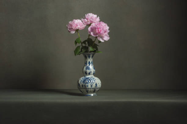 istock Pink peonies in a delft blue vase on a table in a grey room. 1224157070