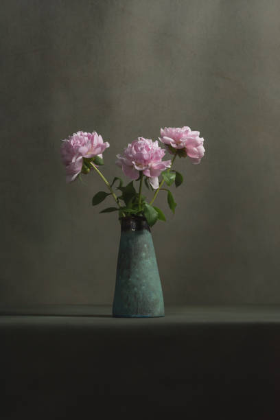 istock Pink peonies in a vintage pottery vase on a table in a grey room. 1224157079
