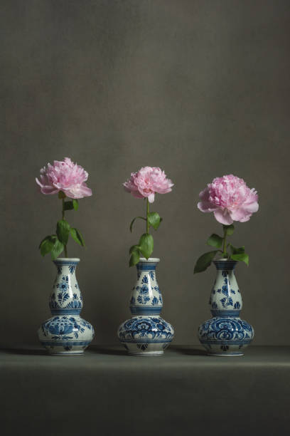 istock Three delft blue vases with pink peonies on a table in a grey room. 1224157083