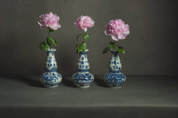 istock Three delft blue vases with pink peonies on a table in a grey room. 1224157104