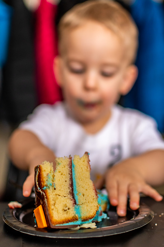Young boy eating cake during his 2nd anniversary party.