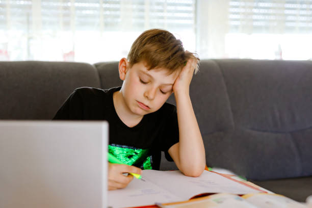 istock Upset school kid boy making homework during quarantine time from corona pandemic disease. Frustrated sad boy learning staying at home with video via laptop. Homeschooling concept 1224161148