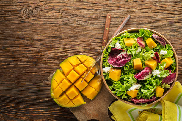 Salad with mango fruit Healthy lettuce salad with mango fruit and fresh cheese on wooden table background. Healthy salad meal. green leaf lettuce stock pictures, royalty-free photos & images