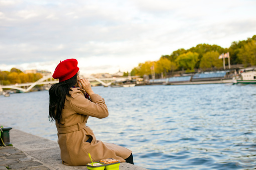 asian traveler eating  a food on the seine river, Paris, France