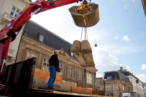 Man on truck operating crane in a narrow street with facades of old houses. Man on truck operating crane in a narrow street with facades of old houses. Copenhagen; Denmark - April 23, 2010. car transporter stock pictures, royalty-free photos & images