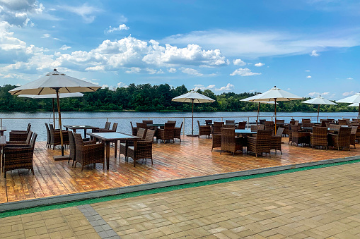 picturesque view of outdoor cafe with rattan chairs and tables on shore of river