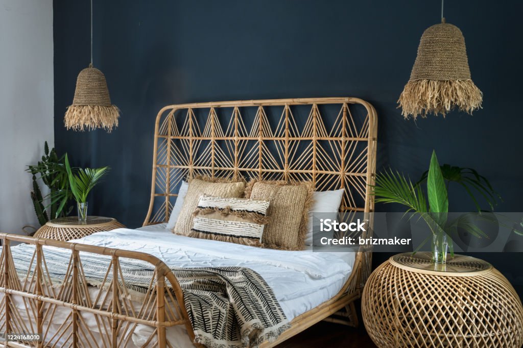 Elegant bedroom interior at cozy house with ethnic decor Bohemian style interior at cozy house with ethnic decor. Elegant bedroom with lamps over bedside tables, pillows at comfortable bed, cactus plant and copy space on deep blue wall Furniture Stock Photo