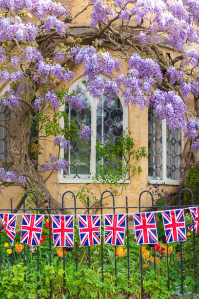 Union Jack Flag bunting hanging on an a wrought iron fence outside an old Cotswold stone terraced bay window to celebrate  the 75th anniversary Victory in Europe’ VE celebrations. Union Jack Flag bunting hanging on an a wrought iron fence outside an old Cotswold stone terraced bay window to celebrate  the 75th anniversary Victory in Europe’ VE celebrations. ve day celebrations uk stock pictures, royalty-free photos & images