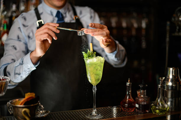 istock Professional bartender decorates green alcoholic drink with ice in glass by powder. 1224169909
