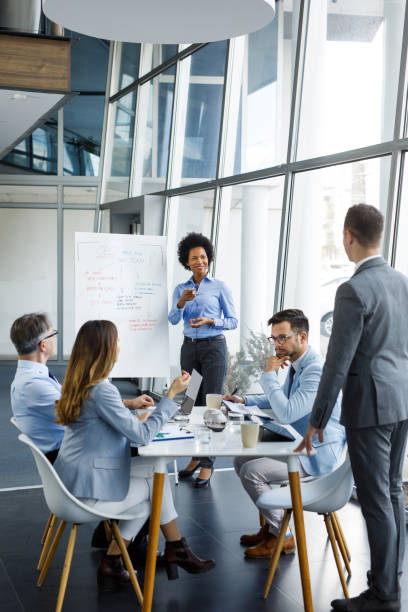 mid adult businesswoman having a brainstorming session with a colleagues in a modern office - business vertical talking usa imagens e fotografias de stock