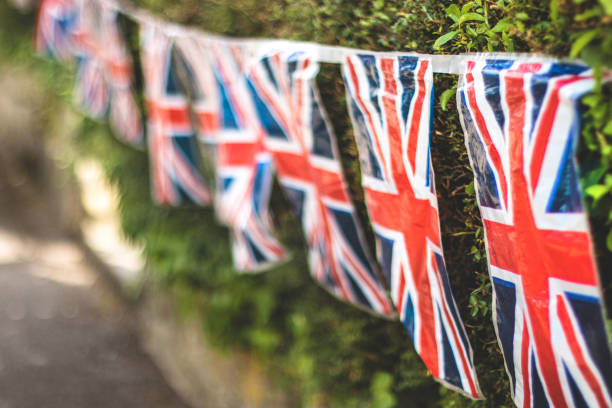 Union Jack Flag bunting hanging from a hedge to celebrate the 75th anniversary Victory in Europe’ VE celebrations.