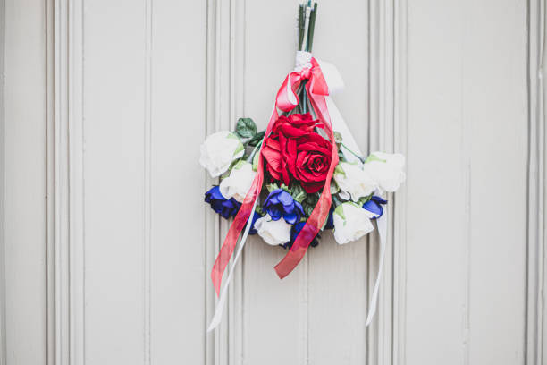 Bunch of Union Jack coloured flowers Flags hanging from a door outside an old Cotswold house to celebrate  the 75th anniversary Victory in Europe’ VE celebrations. Bunch of Union Jack coloured flowers Flags hanging from a door outside an old Cotswold house to celebrate  the 75th anniversary Victory in Europe’ VE celebrations. ve day celebrations uk stock pictures, royalty-free photos & images