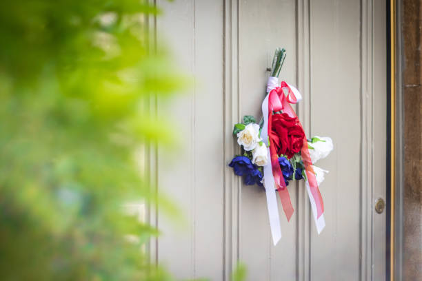 Bunch of Union Jack coloured flowers Flags hanging from a door outside an old Cotswold house to celebrate  the 75th anniversary Victory in Europe’ VE celebrations. Bunch of Union Jack coloured flowers Flags hanging from a door outside an old Cotswold house to celebrate  the 75th anniversary Victory in Europe’ VE celebrations. ve day celebrations uk stock pictures, royalty-free photos & images
