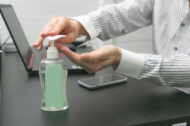 istock Man working from home wearing protective mask. Cleaning her hands with sanitizer gel. 1224174921