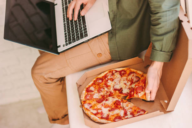 istock Hipster man freelancer eat pizza and work at cozy home workplace 1224175846