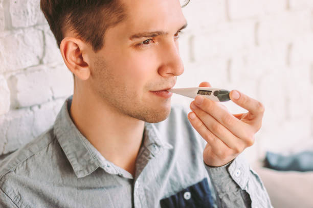 istock Young businessman freelancer put electronic thermometer for temperature check 1224176333