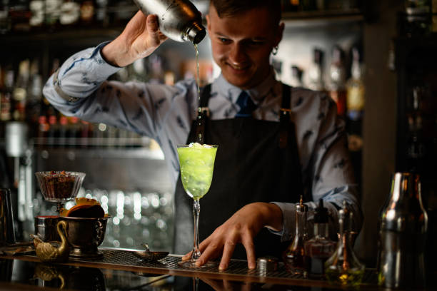 istock young smiling barman pours cocktail from shaker into glass with ice. 1224177834