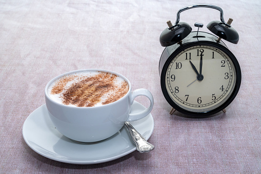 Coffee time - alarm clock with a hot cappuccino