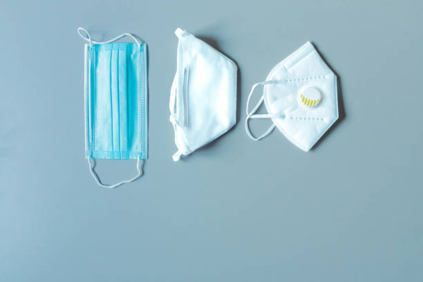 istock Different face masks and respirators with breathing valve on blue background. Protection against virus 1224185430