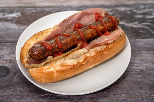 Sausage and bacon bread roll sandwich with tomato ketchup