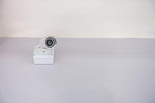 CCTV on white wall close to the ceiling with copy space.