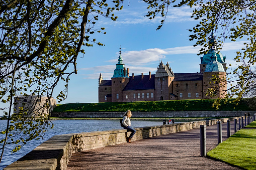 Kalmar, Sweden May 10, 2020 A woman sits on a wall on the grounds of the Kalmar Castle.