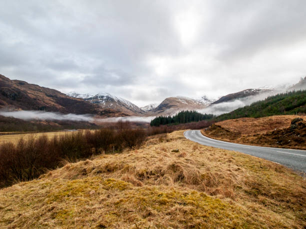 Remote winding road in Glen Nevis, Scotland in winter with mist in the distance