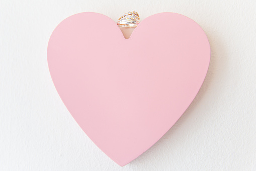 Oro blanco y anillos de boda de diamantes en el corazón de amor rosa photo