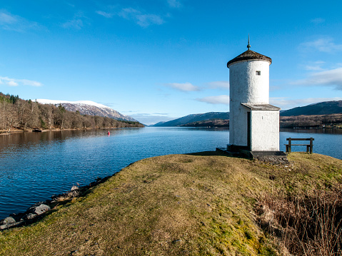 View of Loch Lochy looking northwards with Gairlochy lighthouse in the foreground set against a bright blue sky