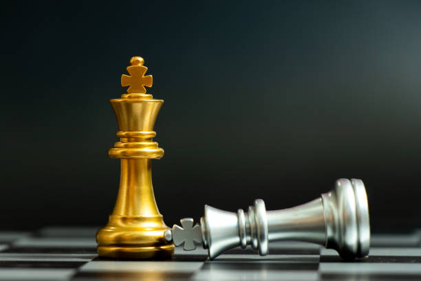 istock Gold king chess piece win over lying down silver king on black background 1224193905