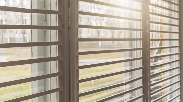 istock shutters hanging on plastic window against street with green grass and bight sunlight 1224197173