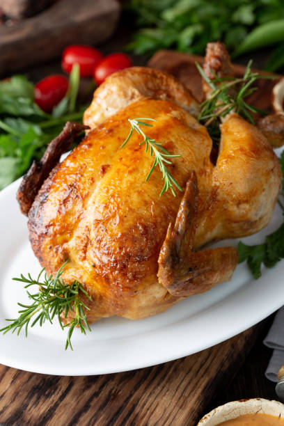 istock Whole Roasted Chicken on white plate with rosemary, sauces and vegetables 1224198736