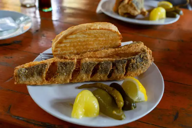 Photo of Balaton style hake ( balatoni hekk ) breaded deep fried fish at a restaurant with sour vegetables pickle and garlic bread toast a typical popular hungarian summer food