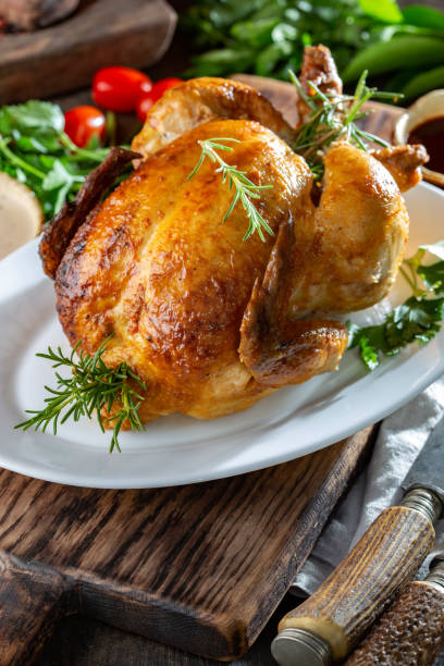 istock Whole Roasted Chicken on white plate with rosemary, sauces and vegetables 1224198848