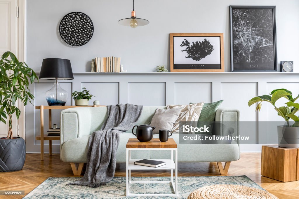 Stylish interior design of living room with modern mint sofa, wooden console, cube, coffee table, lamp, plant, mock up poster frame, pillows, plaid, decoration and elegant accessories in home decor. Stylish interior design of living room with modern furniture, decoration and elegant accessories in home decor. Living Room Stock Photo