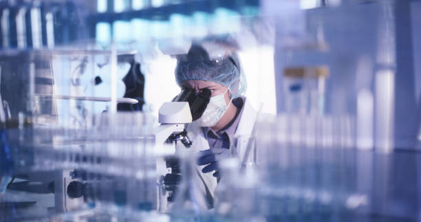 istock Young female microbiologist studying coronavirus - protective workwear 1224202426