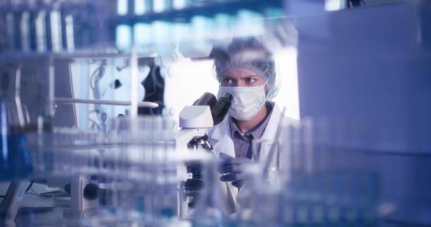 istock Young female microbiologist studying coronavirus - protective workwear 1224202427