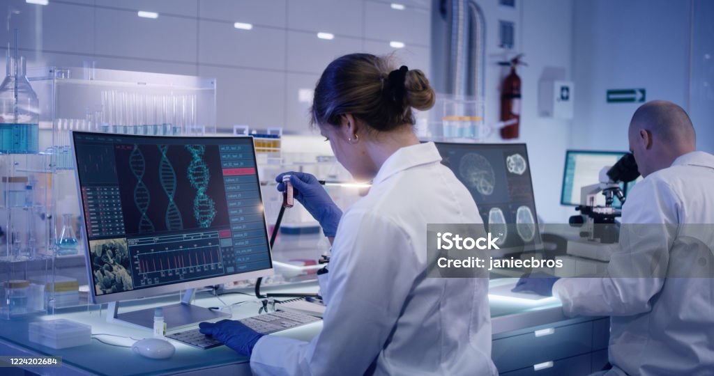 Multi ethnic research team studying DNA mutations. Female doctor in foreground Scientists examines DNA models in modern Neurological Research Laboratory. Healthcare And Medicine Stock Photo