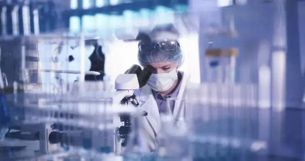 Photo of Young female microbiologist studying coronavirus - protective workwear