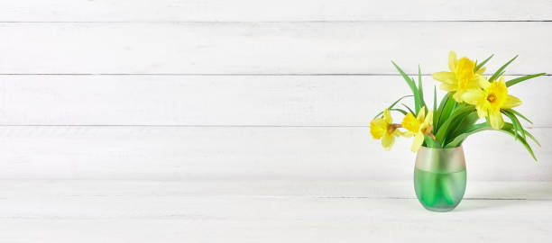 желтые нарциссы на стеклянной вазе на ярко-белом столе на белом деревянном фоне - daffodil bouquet isolated on white petal стоковые фото и изображения