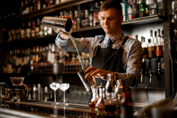 istock young bartender pours cocktail in shaker. Two glasses with ice stand on bar. 1224206943