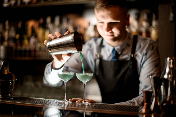 istock young bartender pours cocktail from shaker into glass. 1224208263