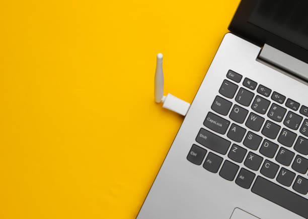 fragment d’un ordinateur portable avec une antenne wifi sur un fond jaune. vue supérieure - usb cable laptop stick computer equipment photos et images de collection
