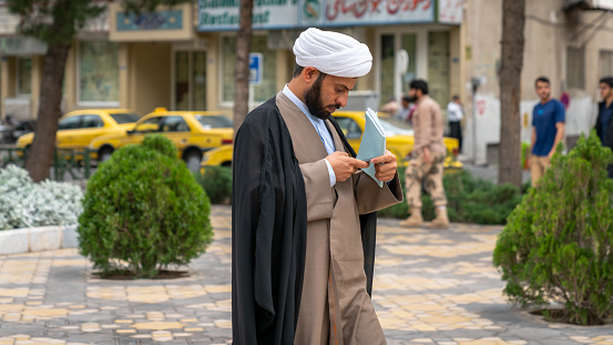 Qom, Iran - May 2019: Iranian man checking his mobile phone in a street in the sacred city of Qom