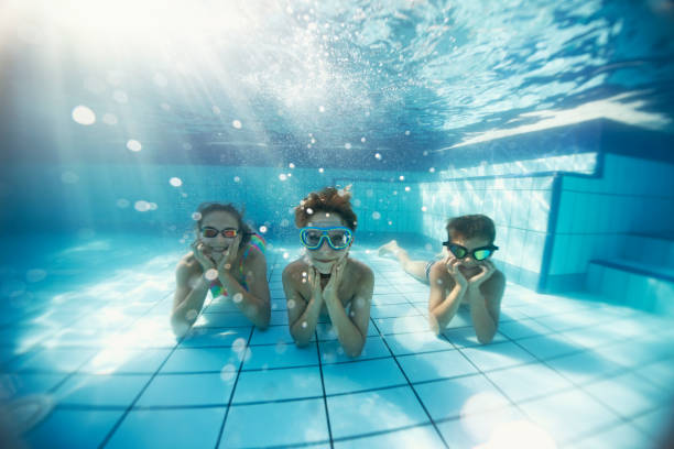 istock Happy kids playing  underwater in a swimming pool 1224210094