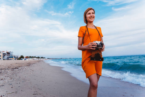 istock Woman with retro camera on the beach 1224210578