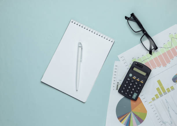 istock Economic analysis, Statistic, analytics. Calculator, glasses and notebook, graphs and charts on a blue background. Top view 1224210623